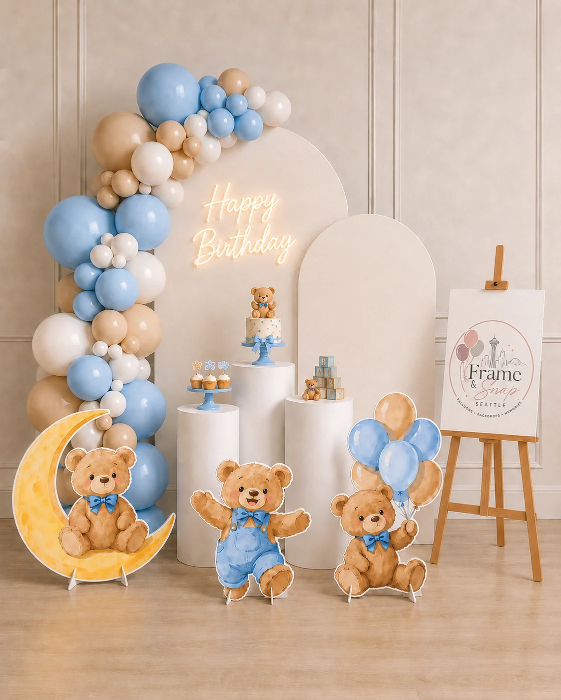 Blue, cream and gold balloons frame curved backdrops, with teddy-bear illustrations and white display plinths.
